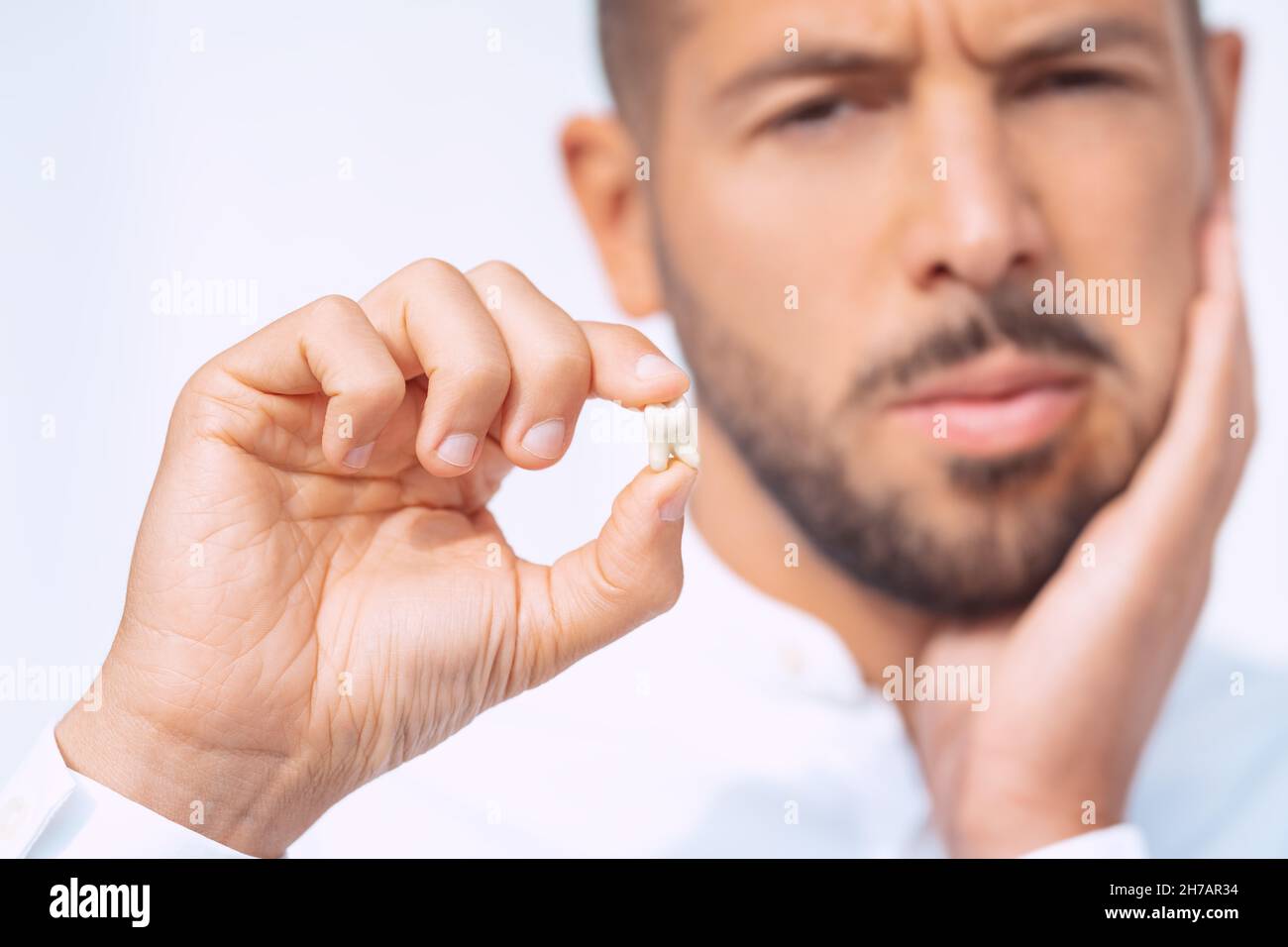 Man with extracted tooth after tooth removal surgery. Pain after tooth extraction Stock Photo