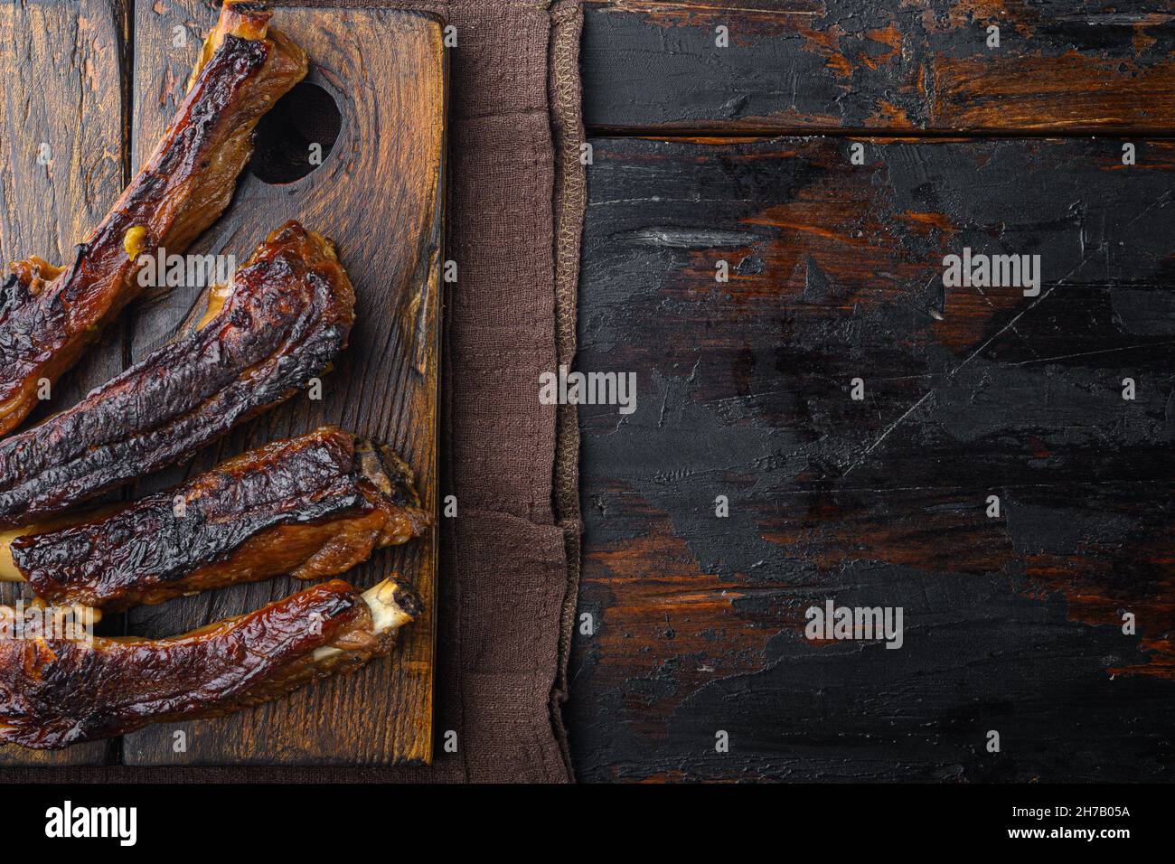 Grilled pork ribs with rosemary and honey set, on wooden serving board, on old dark wooden table background, top view flat lay, with copy space for te Stock Photo