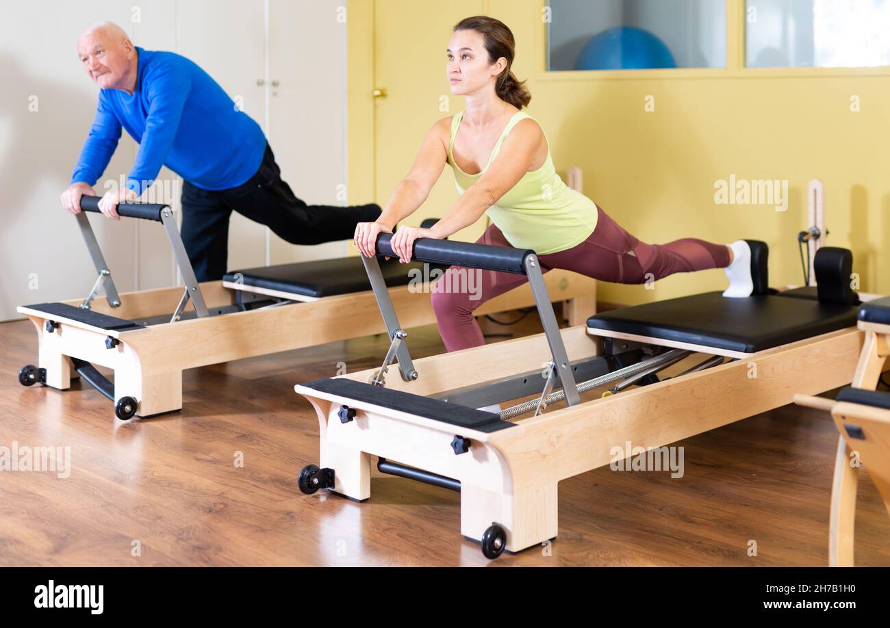 Woman and man doing exercises on Pilates reformer Stock Photo