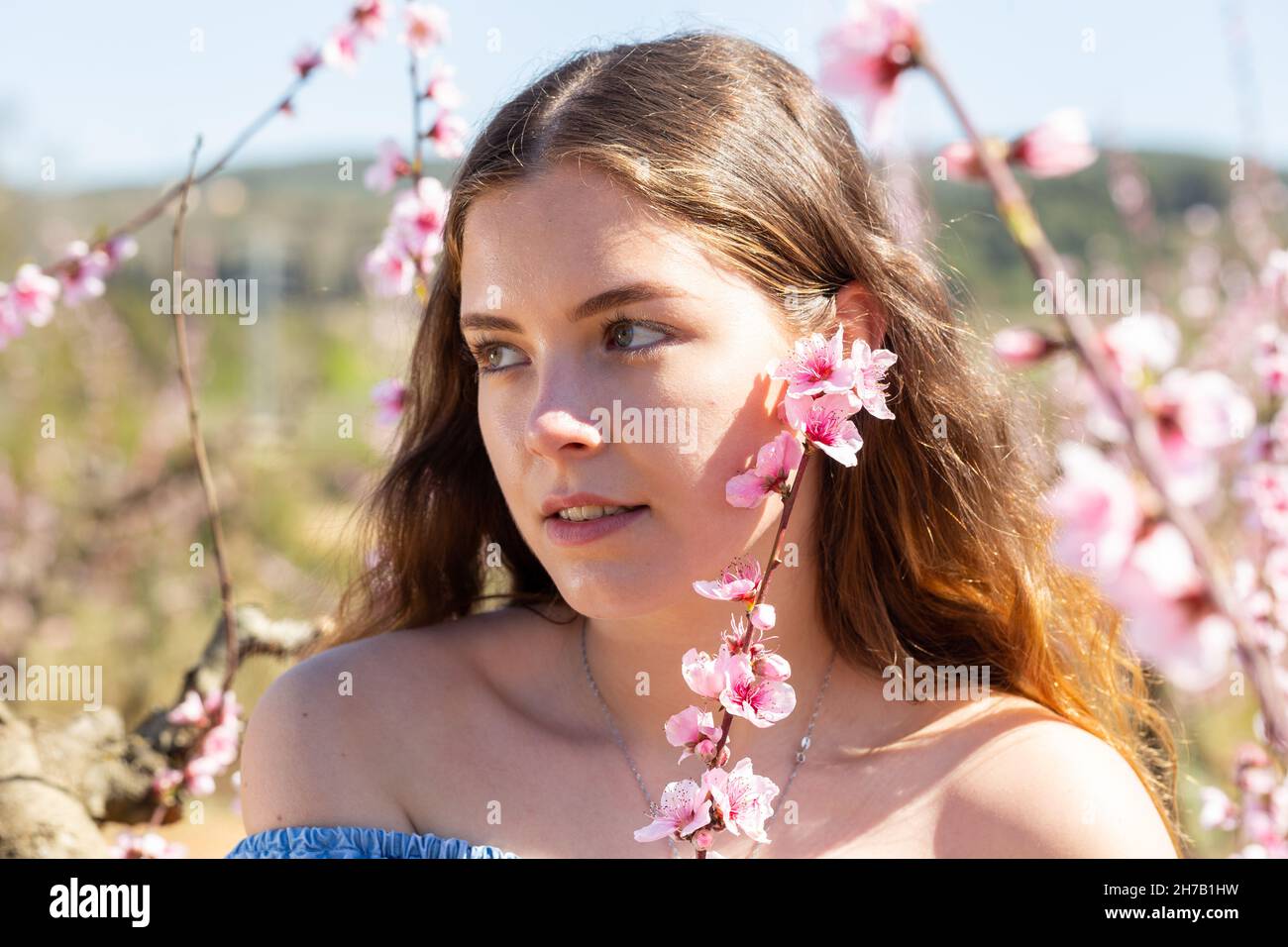 Beautiful blonde girl with long hair in a pink dress in blooming garden ...