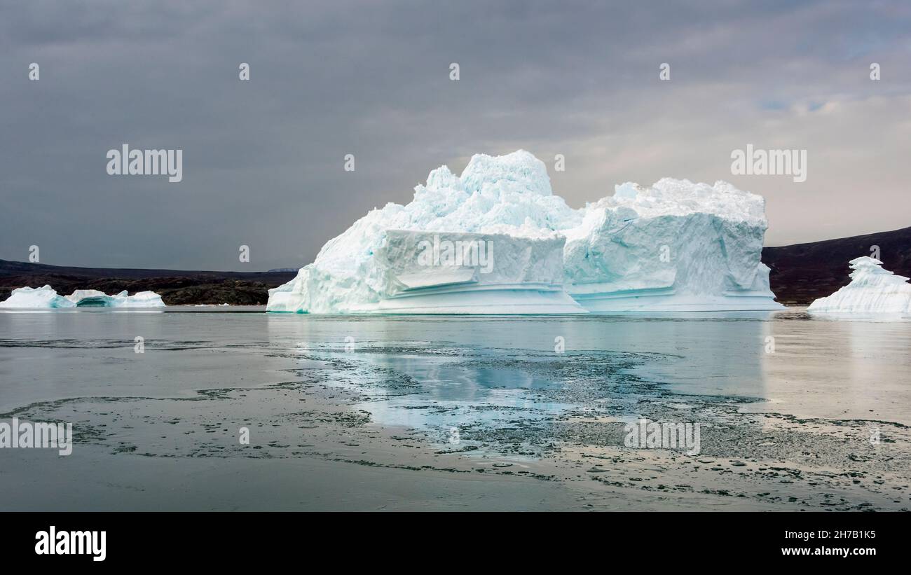 Blue iceberg reflected in sea ice, Rypefjord, Scoresby Sund, Greenland Stock Photo