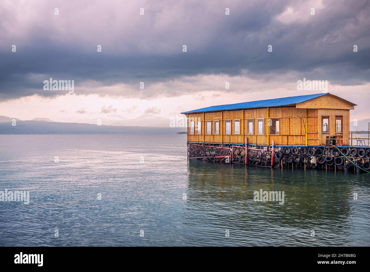 A pier and a wooden house with a restaurant on the shore of Lake Sevan in Armenia. Stock Photo