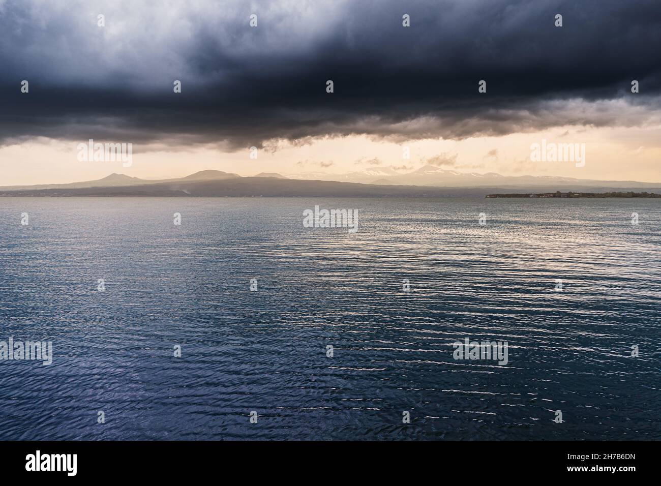 Atmospheric and mood landscape in stormy weather with strong wind on Lake Sevan at sunset. Stock Photo