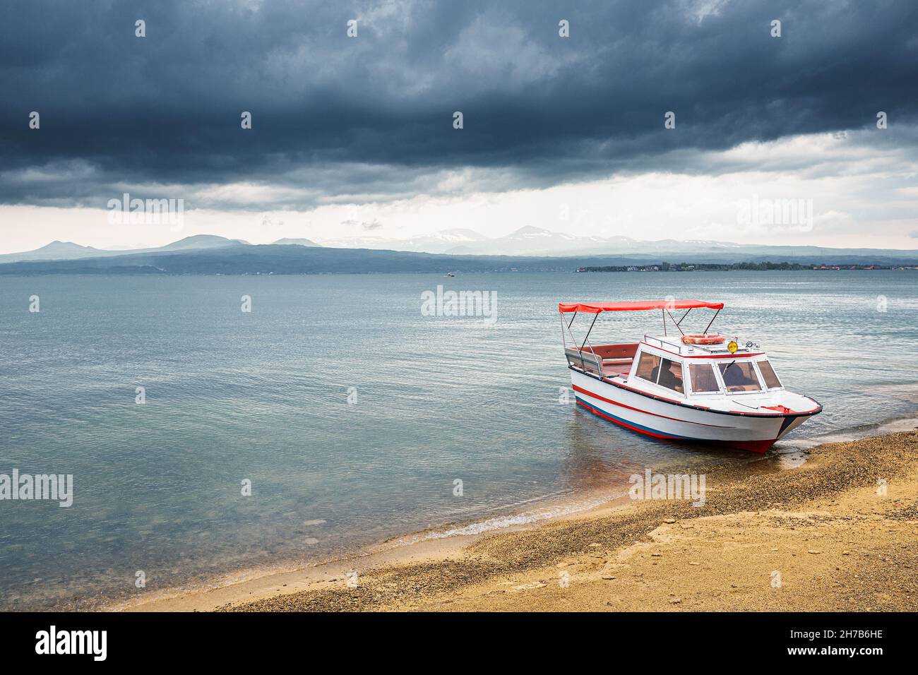 A pleasure boat is waiting for tourists during bad weather on Lake Sevan in Armenia. Water tours and cruises Stock Photo