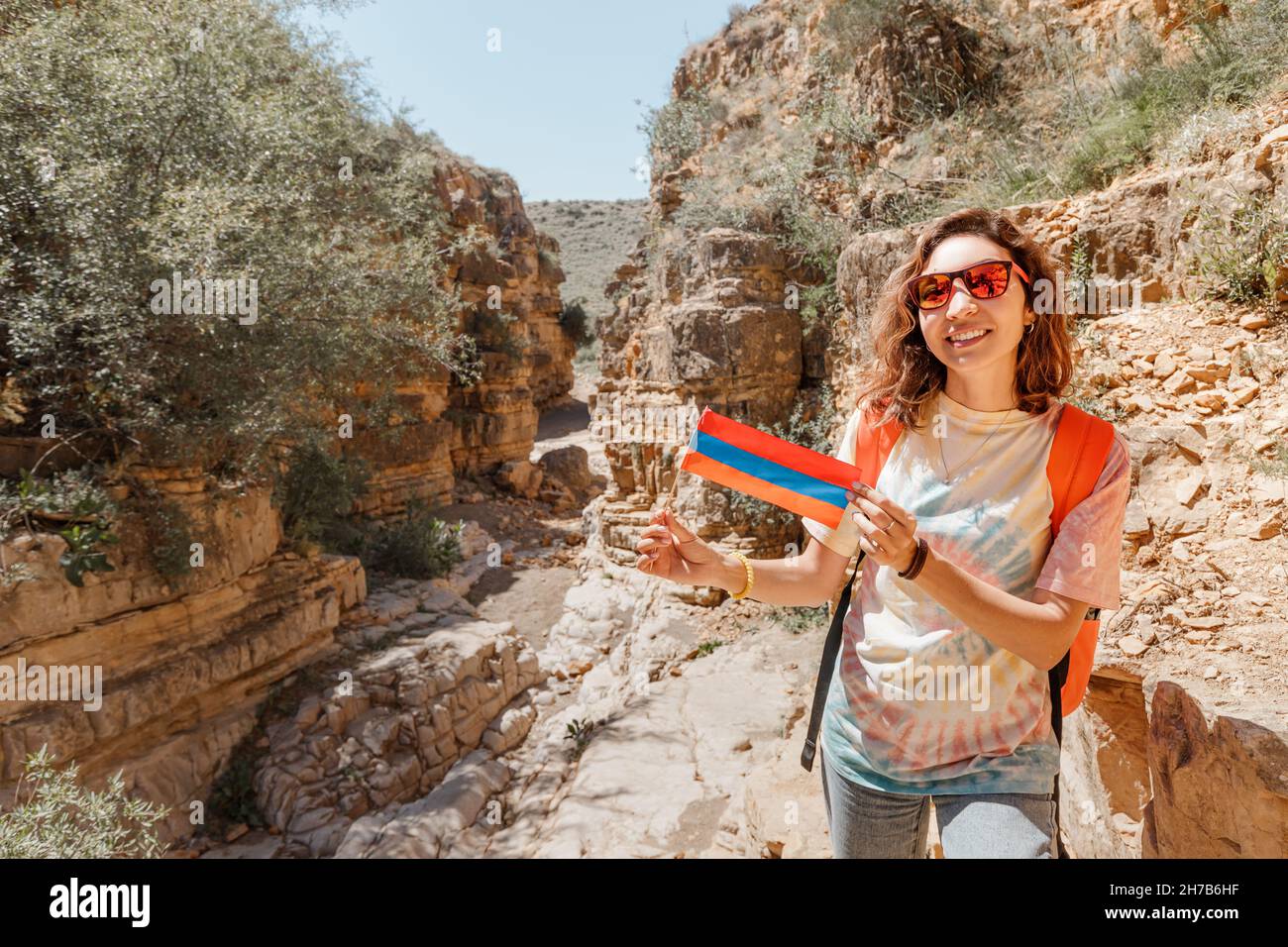 Happy woman with Armenian flag in her hands traveling through the picturesque Angels Canyon in the province of Ararat in Armenia Stock Photo