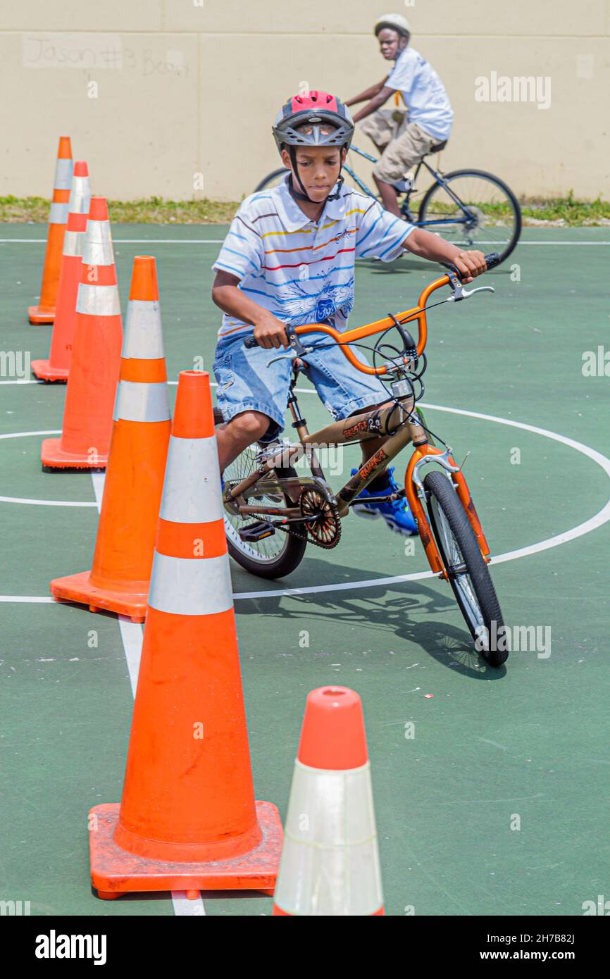 North Miami Beach Florida,Bicycle Rodeo,riding bicycle obstacle course orange traffic cones,Black boys male kids children safety helmet students Stock Photo