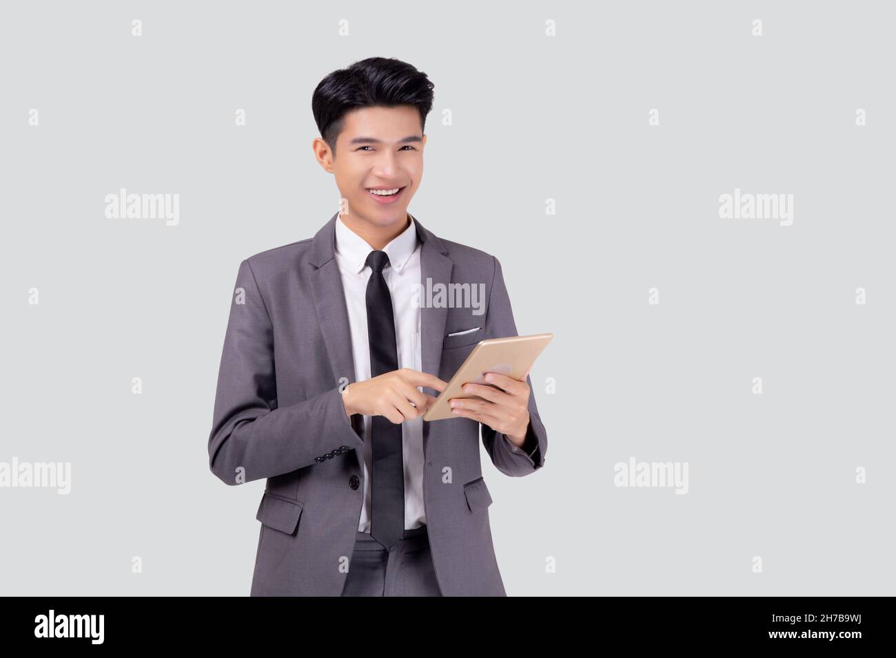 Portrait young asian business man in suit standing using tablet ...
