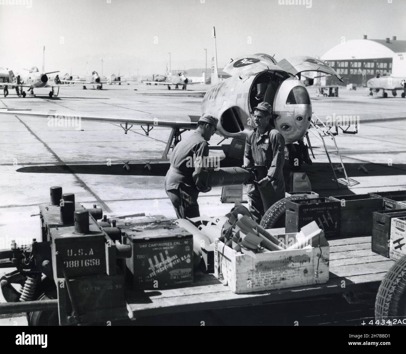 Two airmen armorers hastily load an F-80 Shooting Star jet fighter with practice bombs at Nellis Air Force Base, Nevada, now part of the recently organized crew training Air Force. The “bombs” will be dropped on gunnery range targets near Nellis, thus giving pilots maximum benefit of realistic training, the best next to actual combat. Pictured left to right are A l/c Paul Hathaway and A 3/c Frederick Kruse. Photo released, 28, July 1952 Stock Photo
