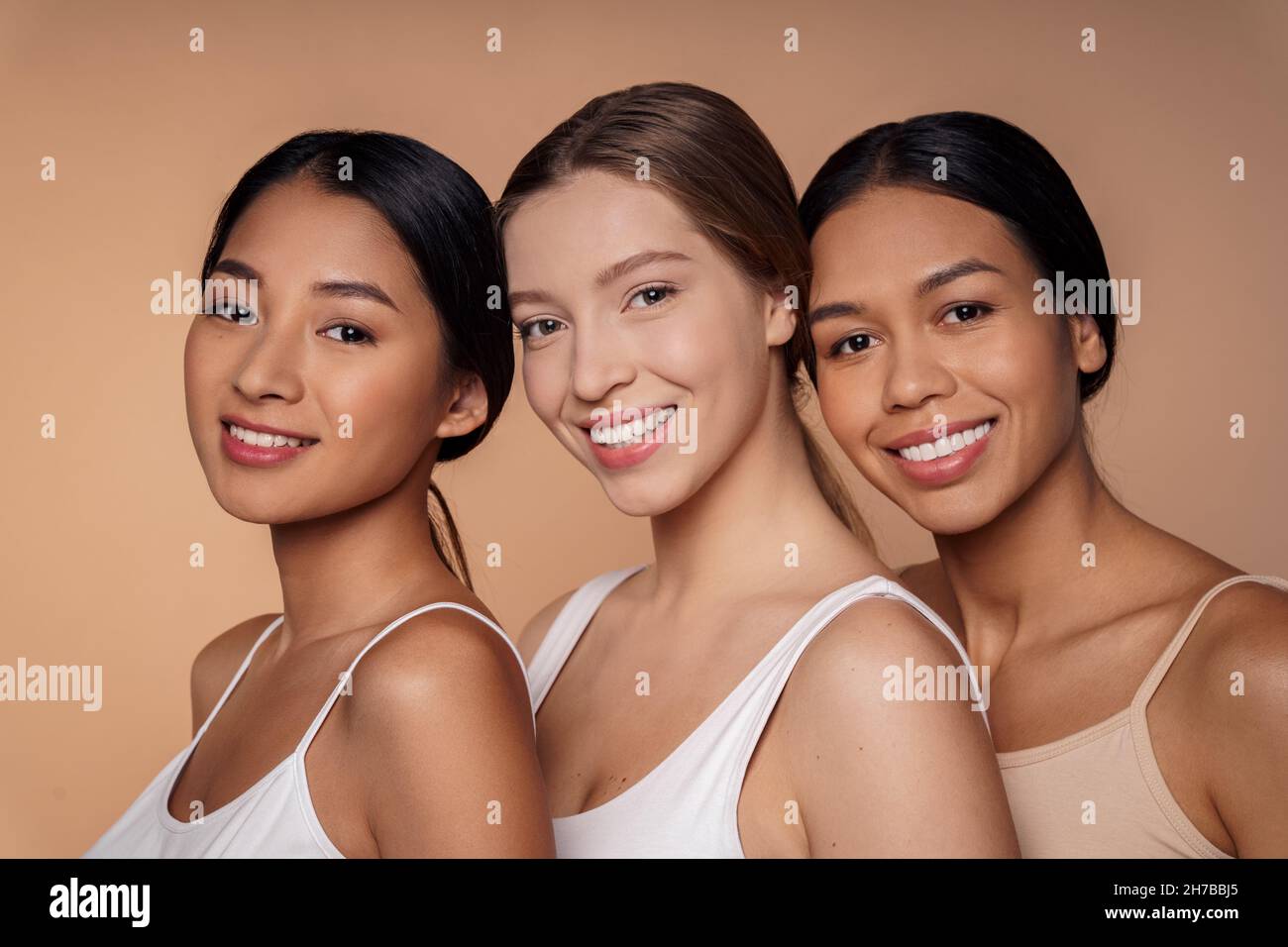 Portrait of there multi-ethnic beautiful young women hugging, smiling to camera Stock Photo