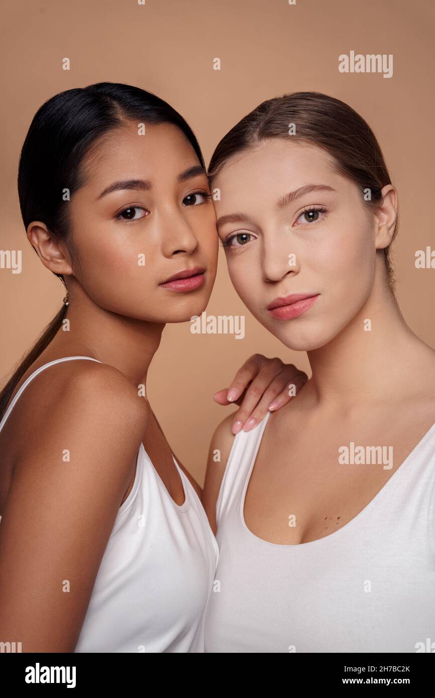 Different ethnicity young women demonstrate healthy face skin looking at camera Stock Photo