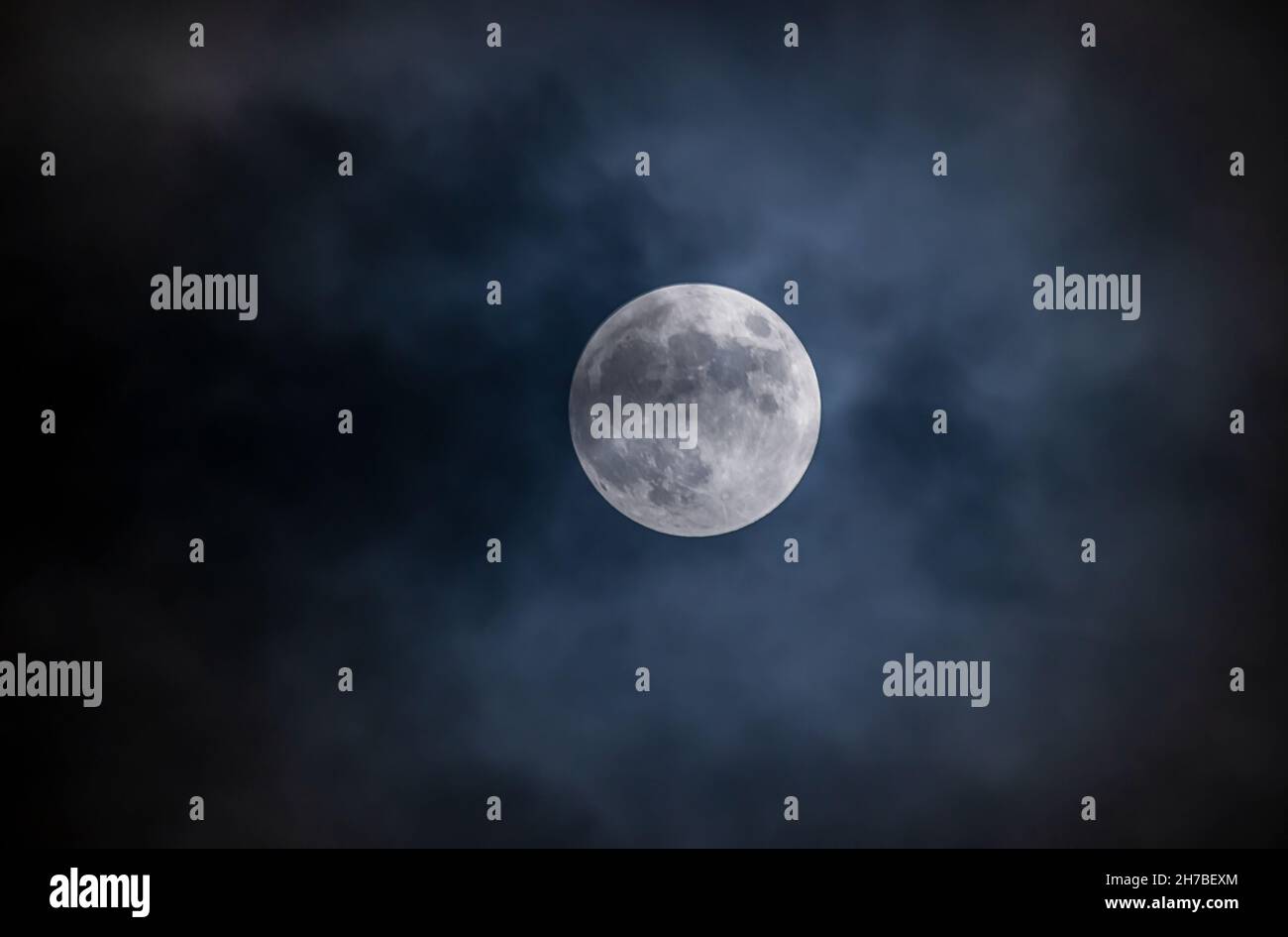 Full moon against the black cloudy night sky Stock Photo