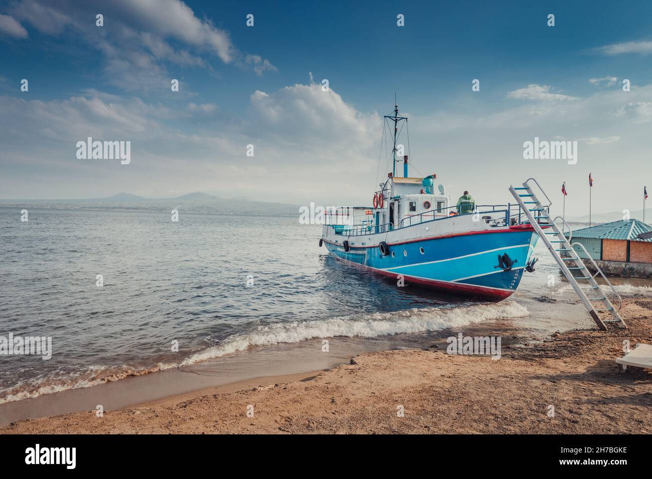 Ferryboat ship is waiting for tourists on the shore of Lake Sevan in Armenia. Water tours and cruises Stock Photo