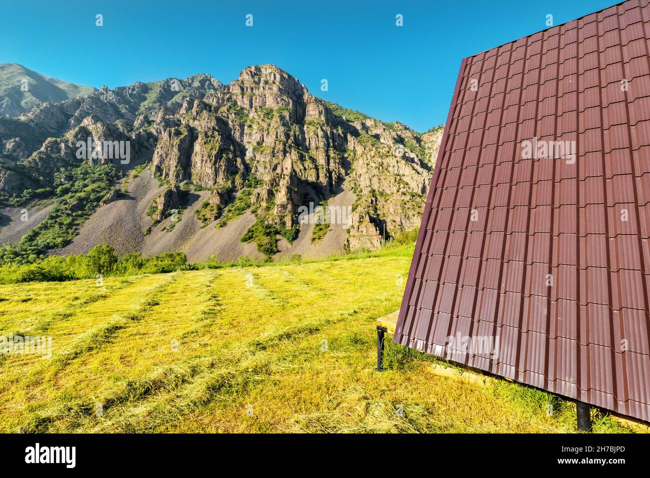 view of a small wooden chalet house roof in the mountains. Concept of glamping and idyllic holidays outdoors Stock Photo