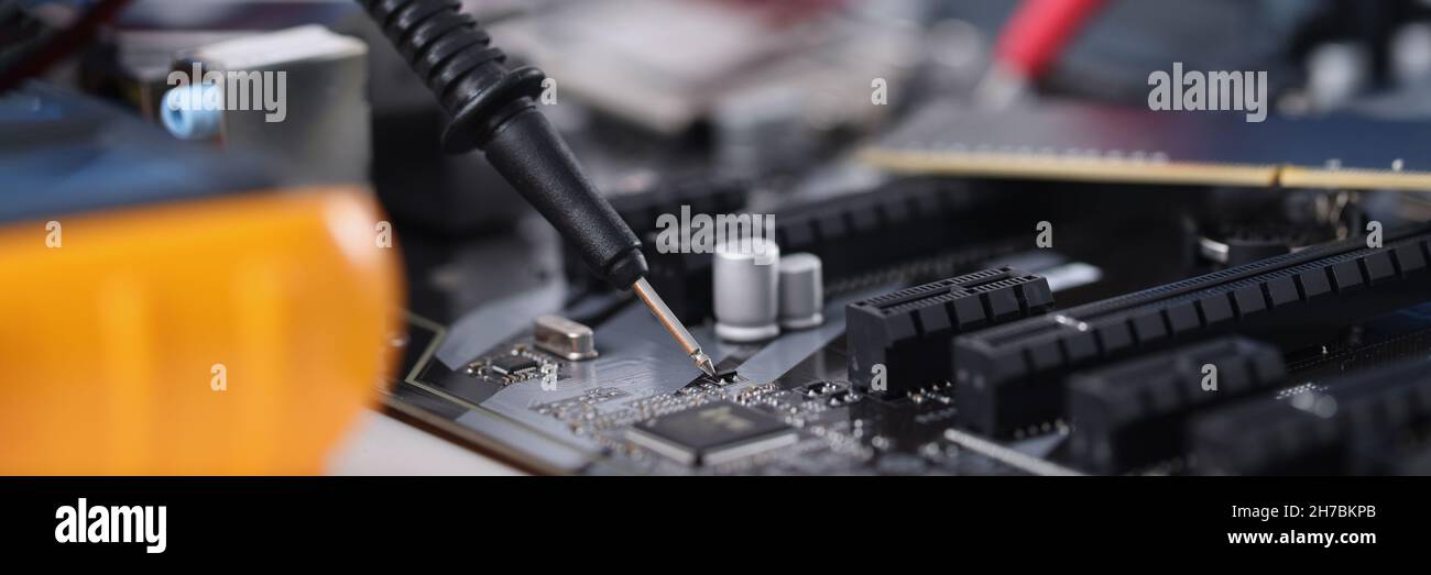 Master in gloves with equipment is testing computer motherboard Stock Photo