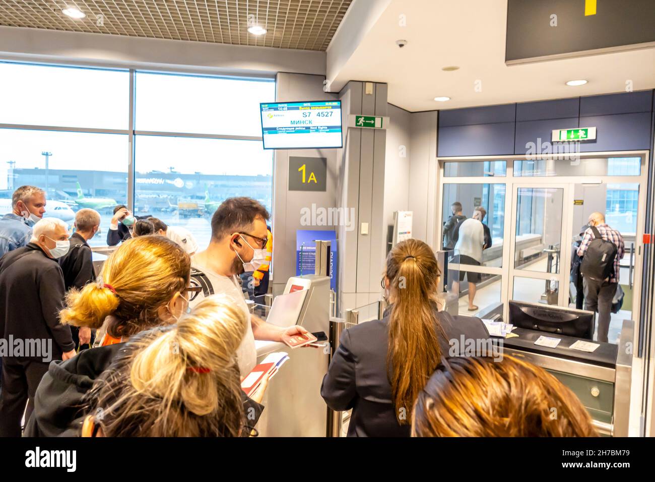 Passengers in face masks are checked for their tickets and passports at the Gate 1A to board on the flight in Domodedovo Airport, DME, Moscow, Russia Stock Photo