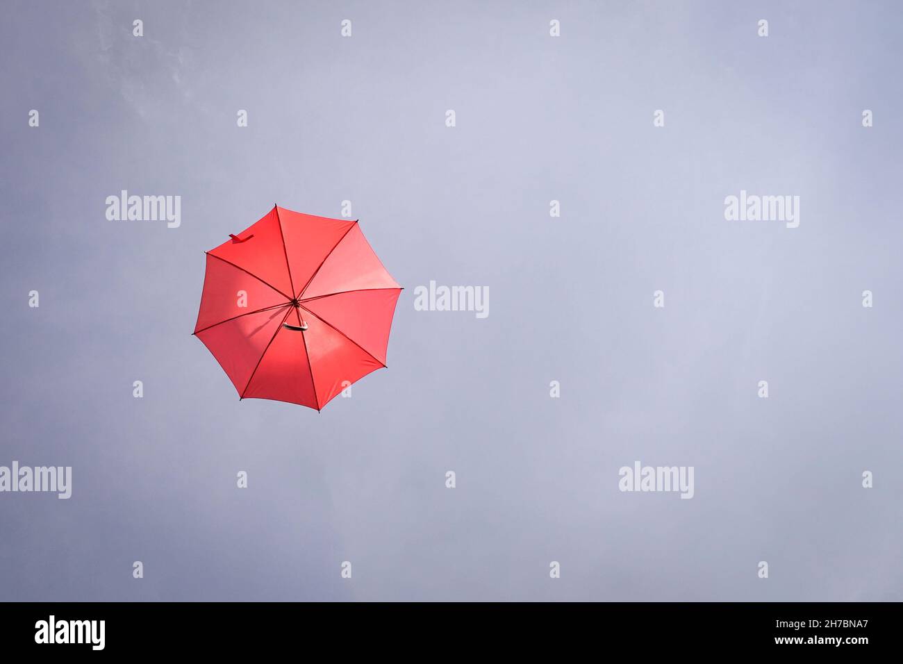 Red umbrella on blue sky. Copy space. Stock Photo