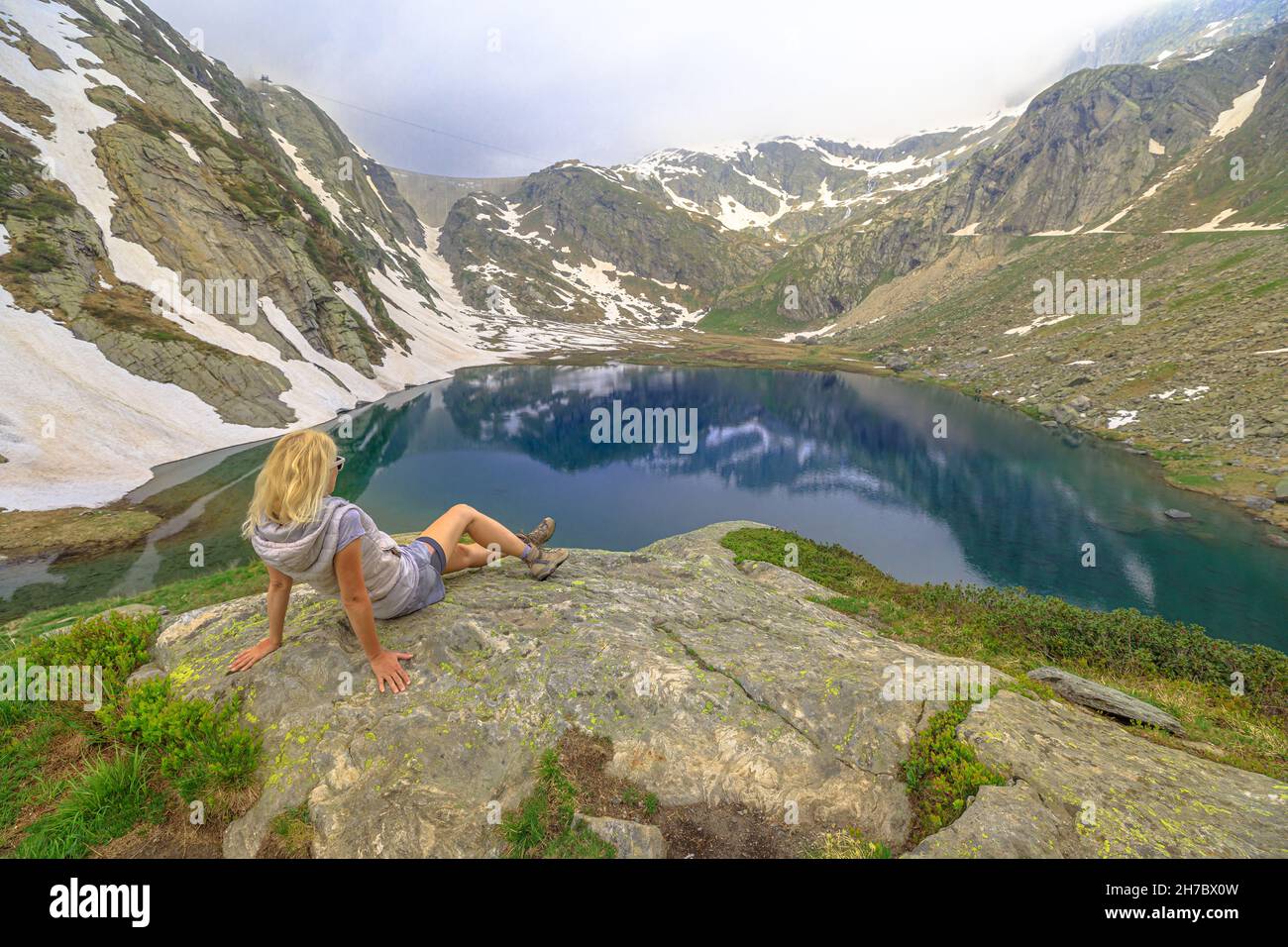 Tourist woman resting during the trekking around the Robiei lake or White Lake. Swiss reservoir of Maggia Valley. Ticino canton of Switzerland with Stock Photo