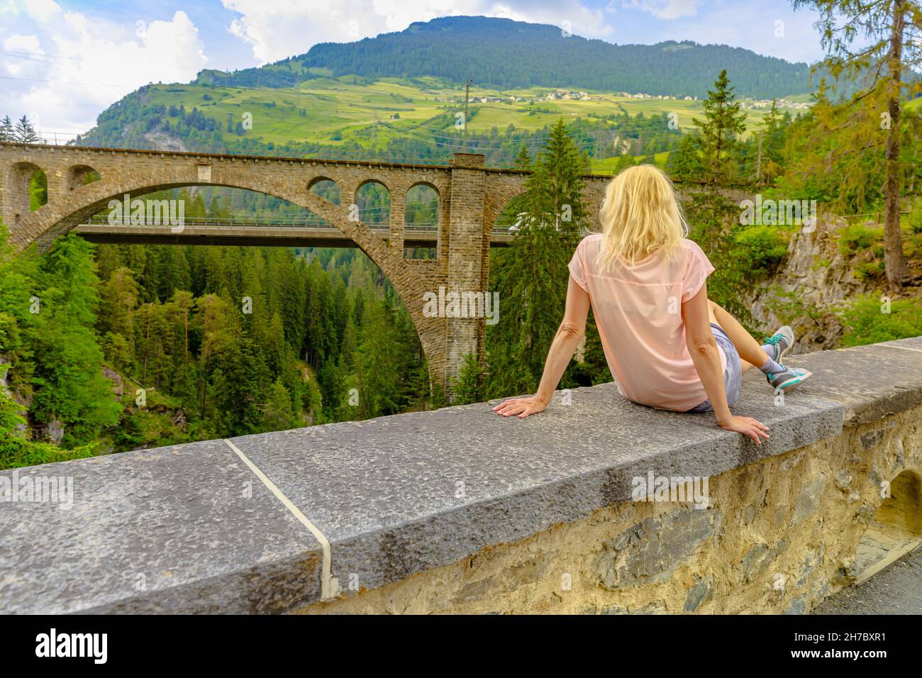 Woman at Solis Viaduct bridge of Swiss railway in Switzerland. Swiss train Bernina and World Heritage in mounts of Grisons canton. Albula Railway by Stock Photo