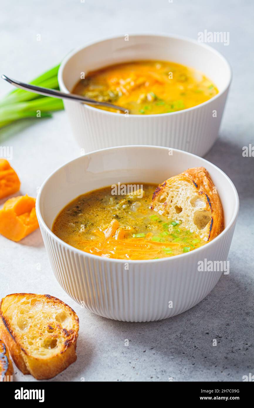 Homemade broccoli cheddar cheese soup with green onions in a white bowl