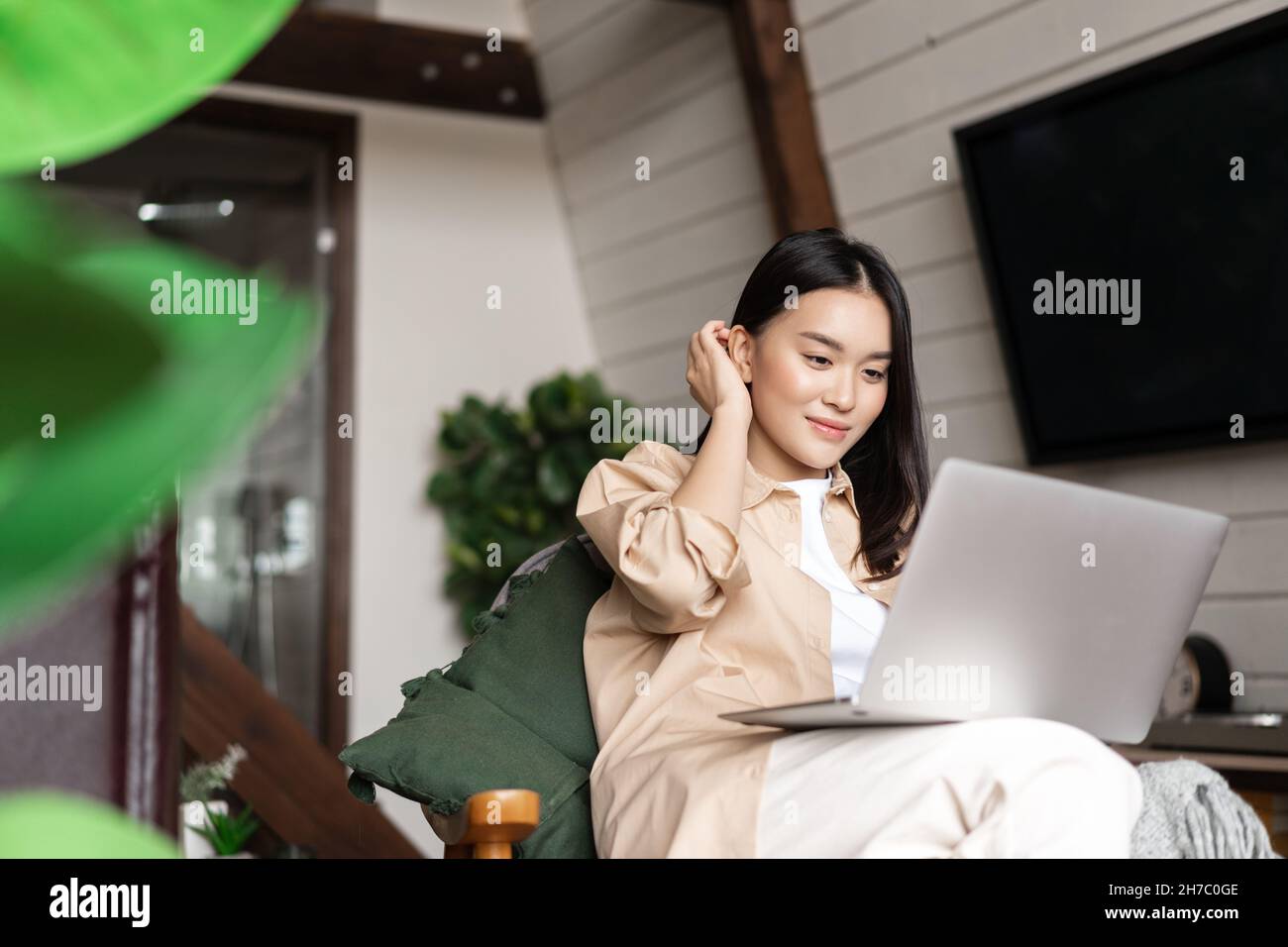 Young asian woman sitting at home with laptop computer. Girl browsing ...