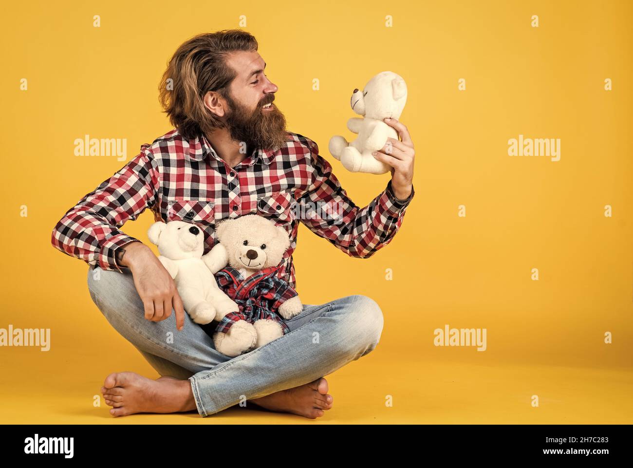 brutal bearded man wear checkered shirt having lush beard and moustache with teddy bear toy, toy shop Stock Photo
