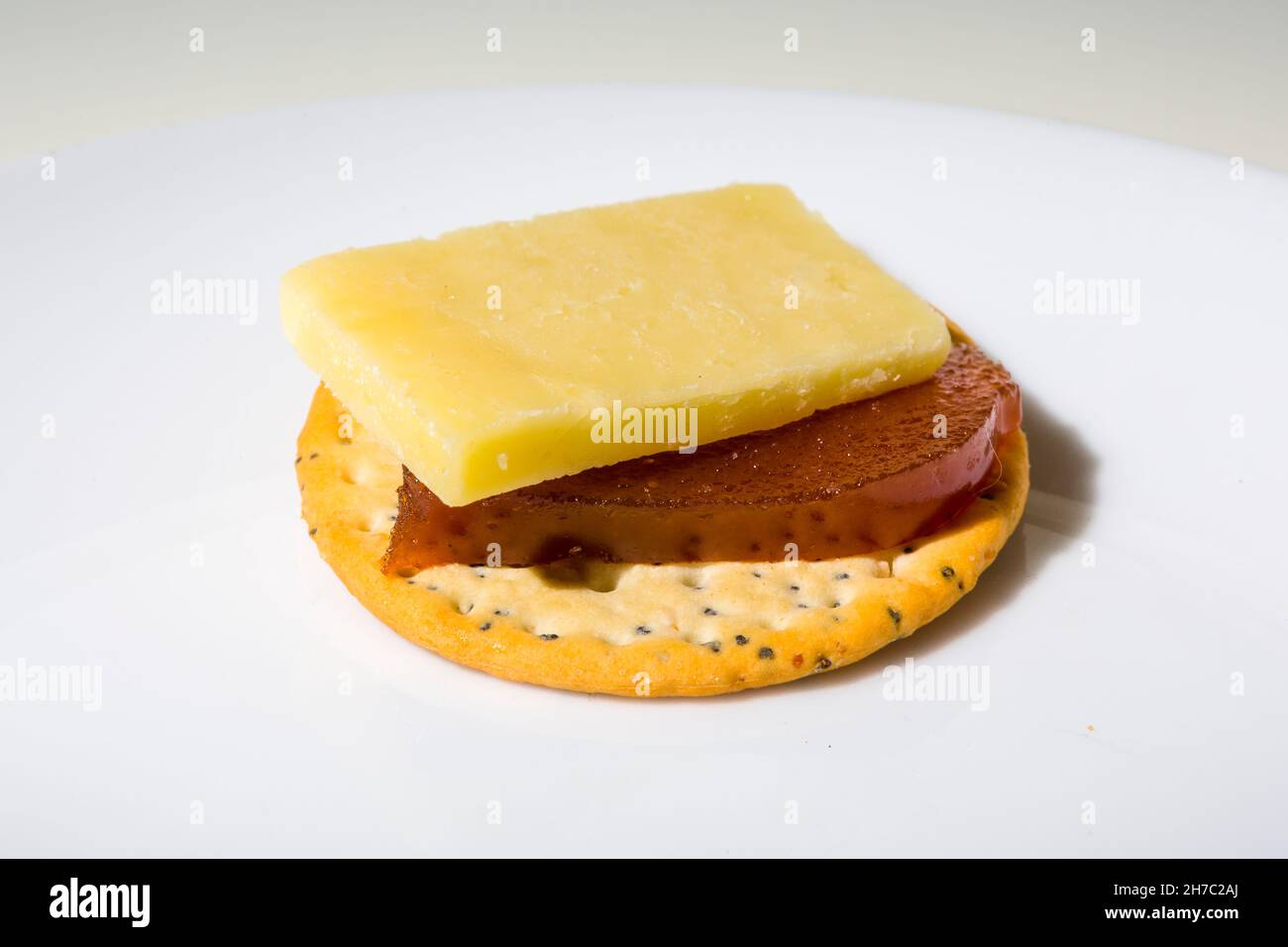 Cheese and a slice of quince jelly on a poppy and sesame seed biscuit. Stock Photo
