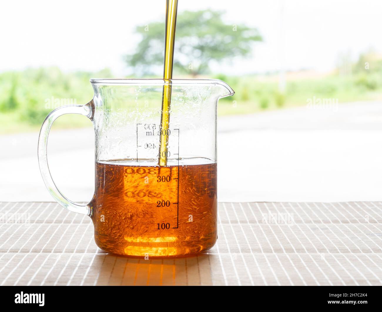 Chicken oil being poured into a glass jug. Chicken oil is made from