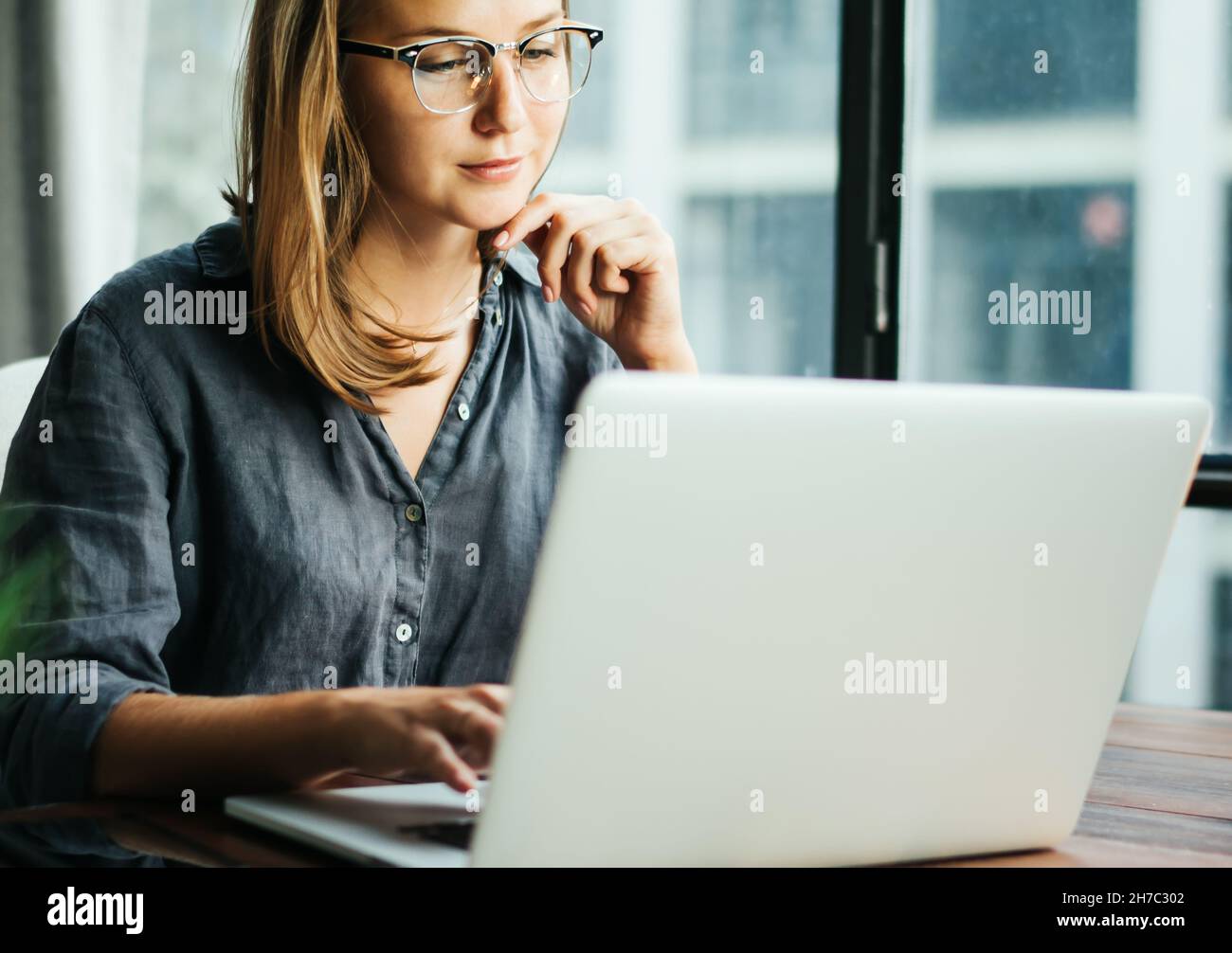 Young woman working with a laptop. Female freelancer connecting to ...