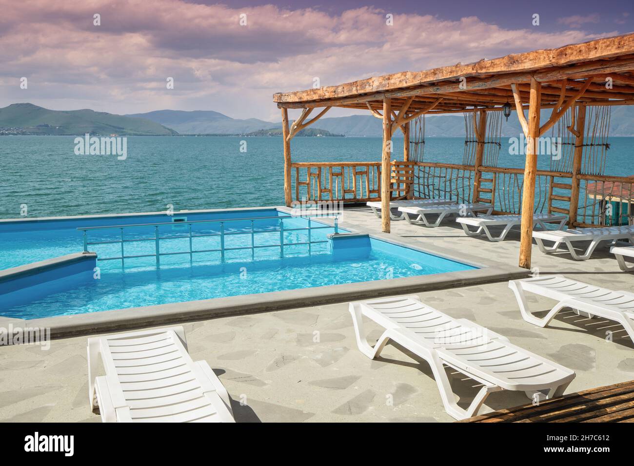Sun loungers and sunbeds near the swimming pool with view on Lake Sevan in Armenia. Rest and vacation concept Stock Photo