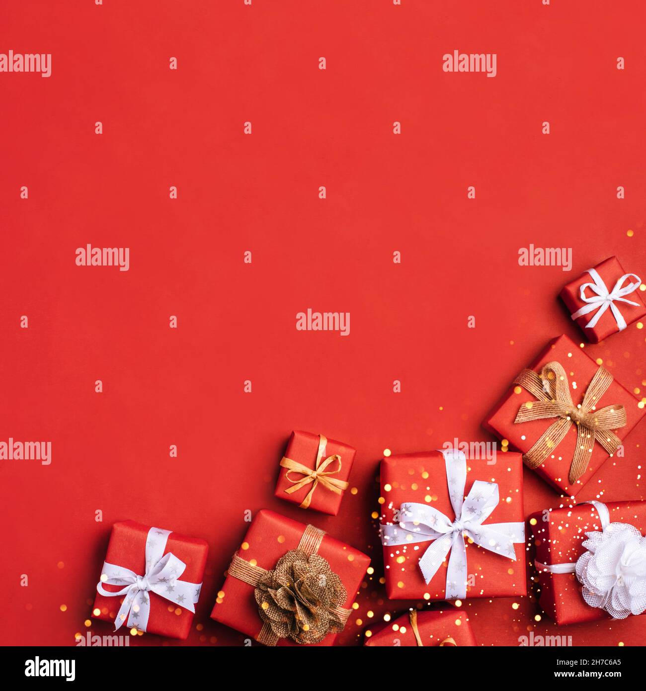 Gift boxes with white and brown bows on a red backdrop. Stock Photo
