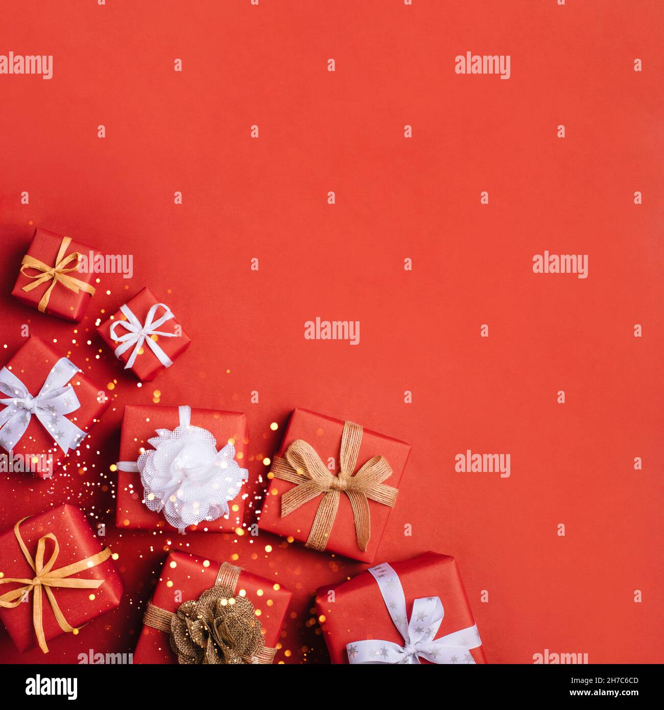 Gift boxes with white and brown bows on a red backdrop. Stock Photo