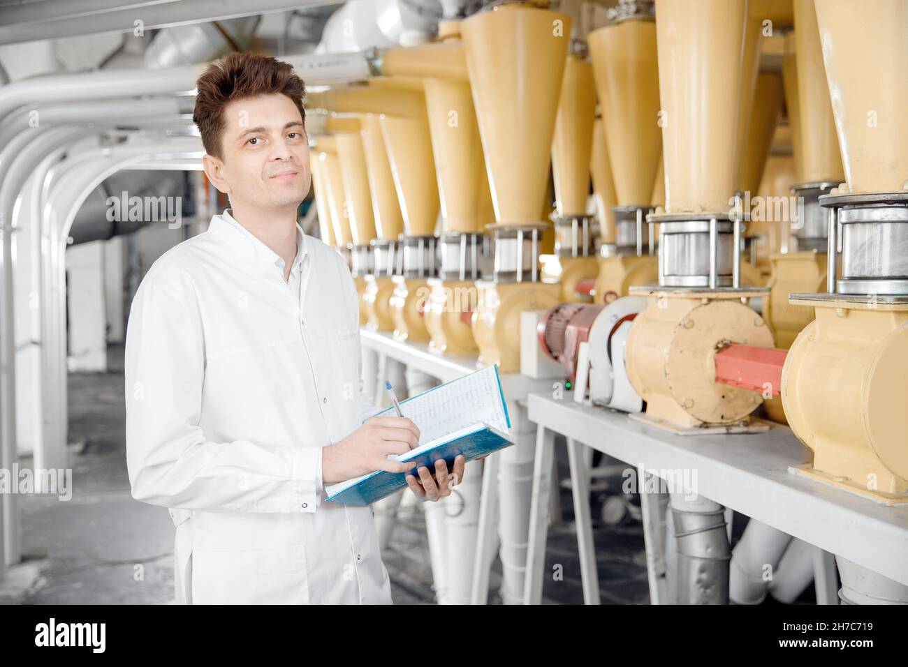 Worker operator checks mill production line of cereals, flour, millet and seeds. Food industry
