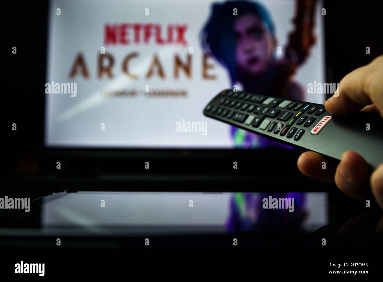 TV remote controller and Arcane Netflix TV series in background. The origins of two iconic League champions, set in the utopian Piltover and the oppre Stock Photo