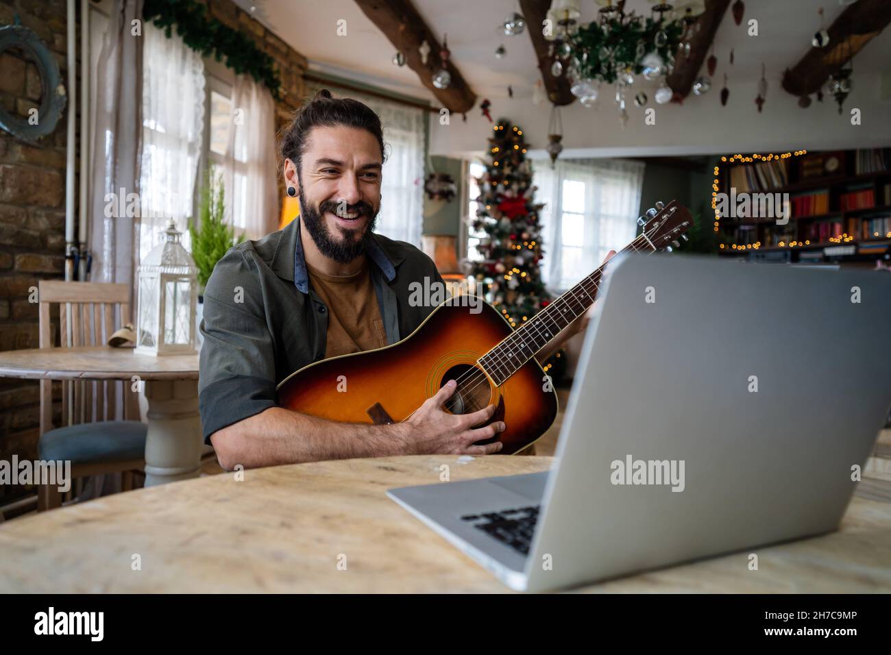 Portrait of a man taking guitar lessons online in a room at home Stock Photo