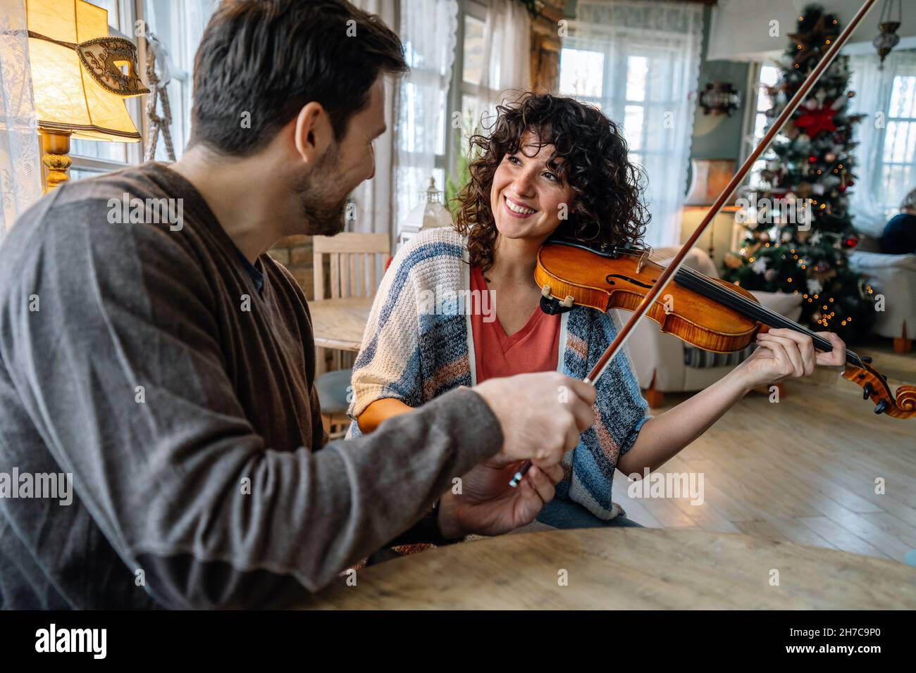 Private male music teacher giving violin lessons to a woman at home ...