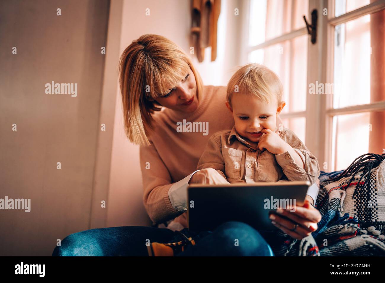 Happy family technology concept. Smiling mother and her toddler son playing with digital tablet Stock Photo