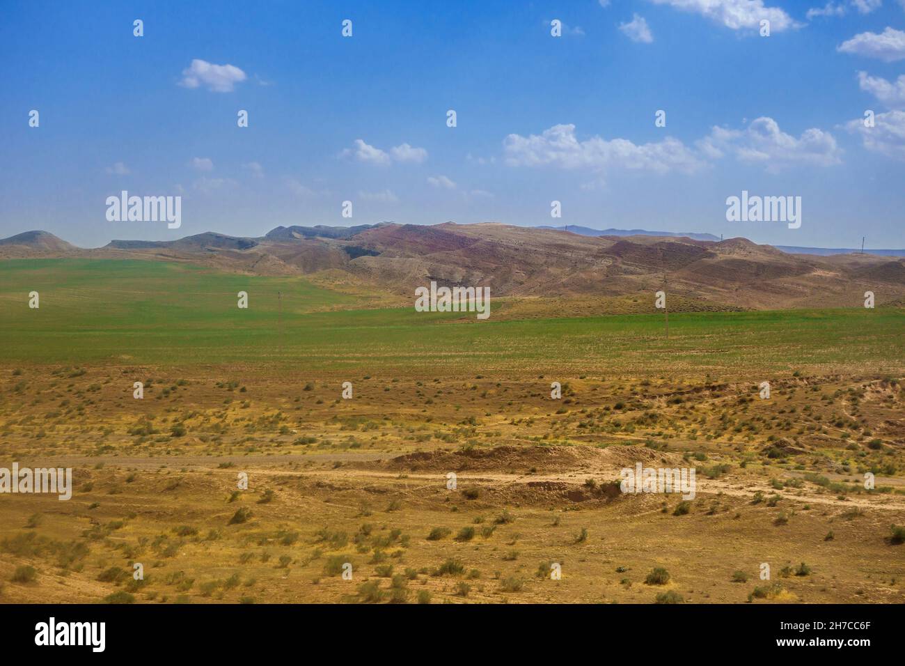 Deserted steppe, giving way to green pasture at the foot of the Gissar ridge. Shot in the Surkhandarya region of southern Uzbekistan Stock Photo