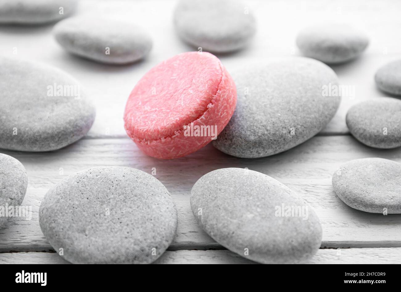 Pink color solid shampoo, conditioner bar on flat sea stones. Minimalist beauty set indoors. Shallow depth of field. Stock Photo