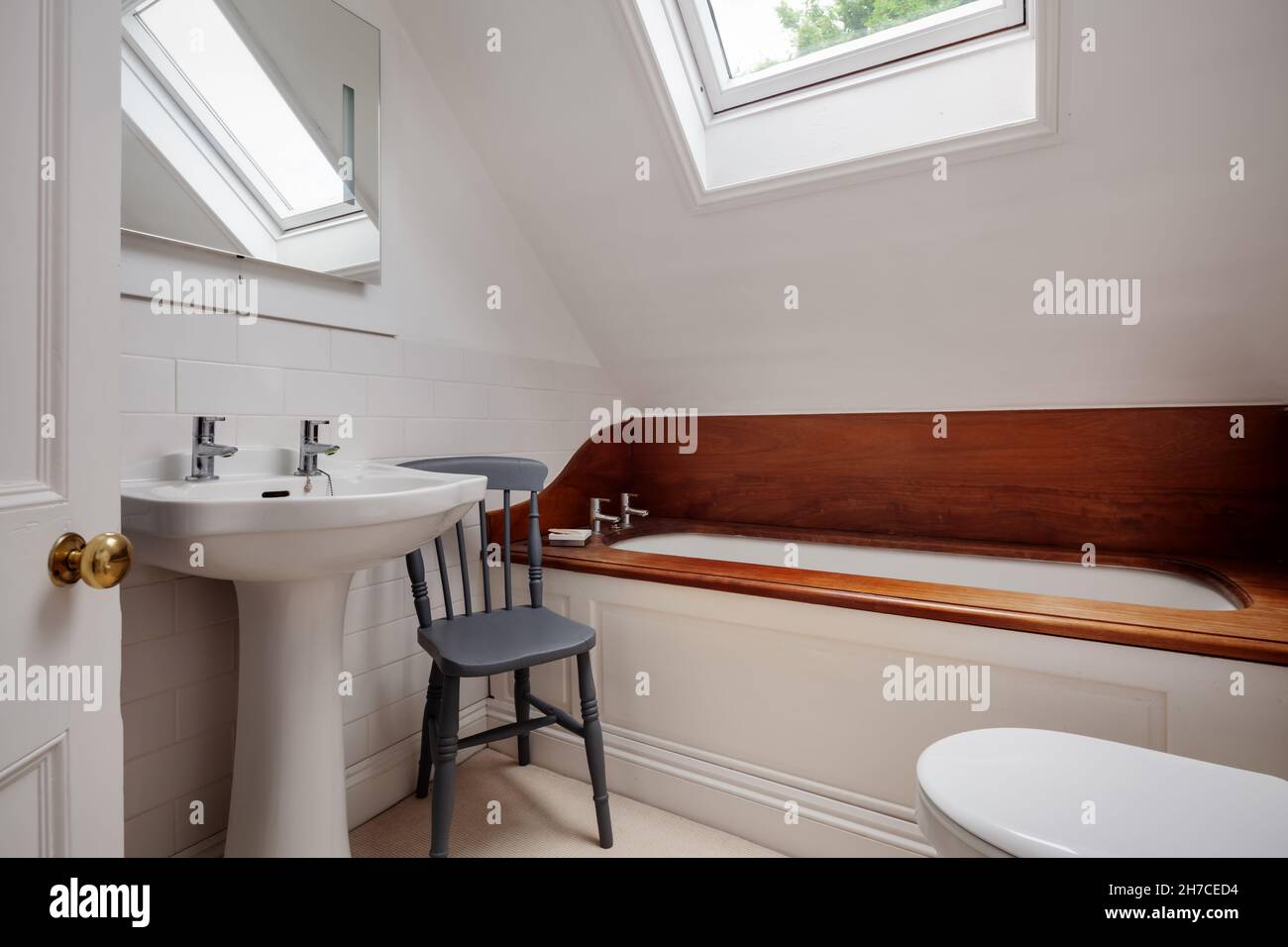 Stradishall, Suffolk, England - 16 June 2020: Traditional compact bathroom with interesting wooden bath surround and splash back Stock Photo