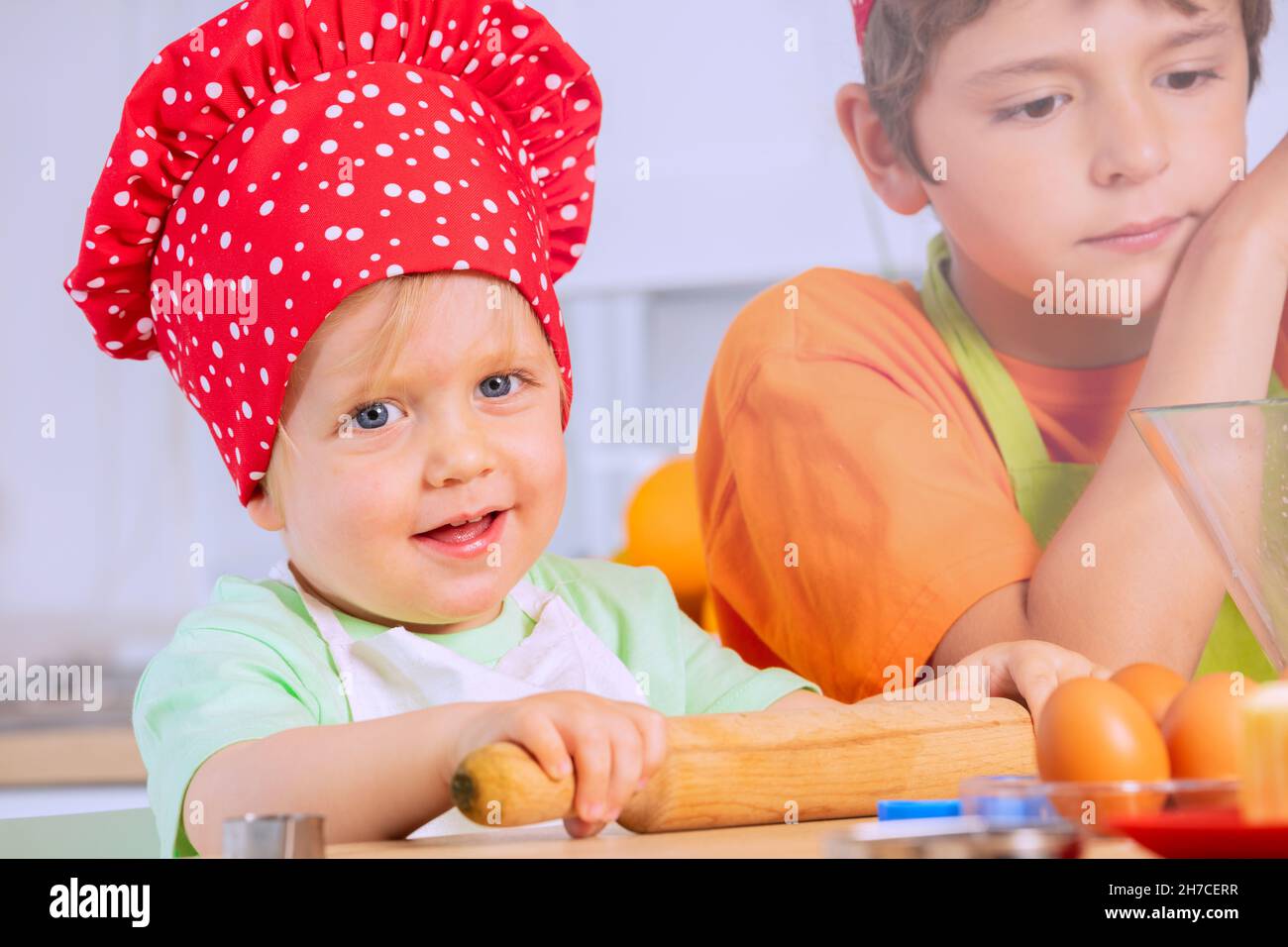 Small toddler boy roll dough plunger in chef hat Stock Photo