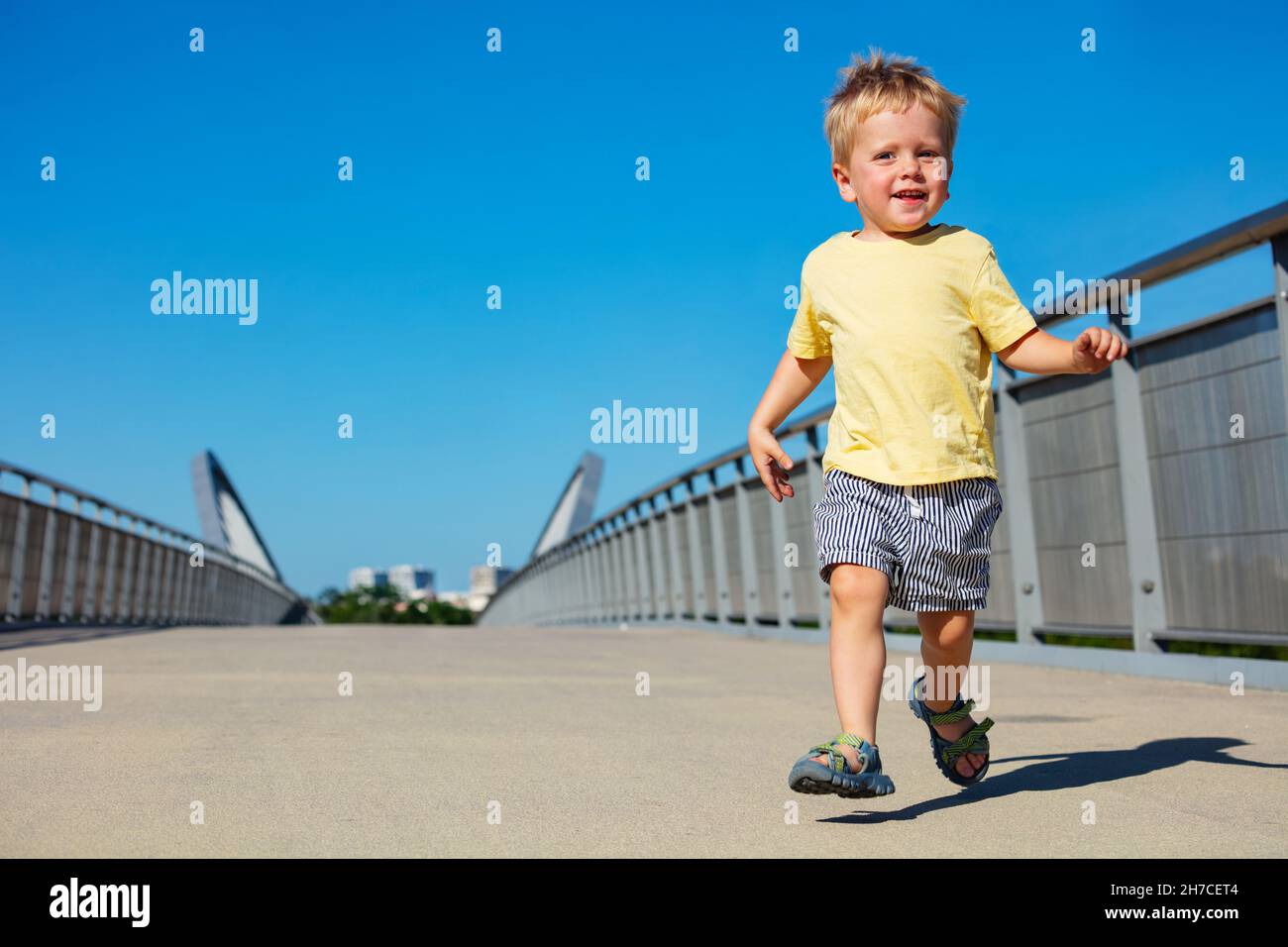 Blond toddler boy run on the pedestrian bridge Stock Photo Alamy