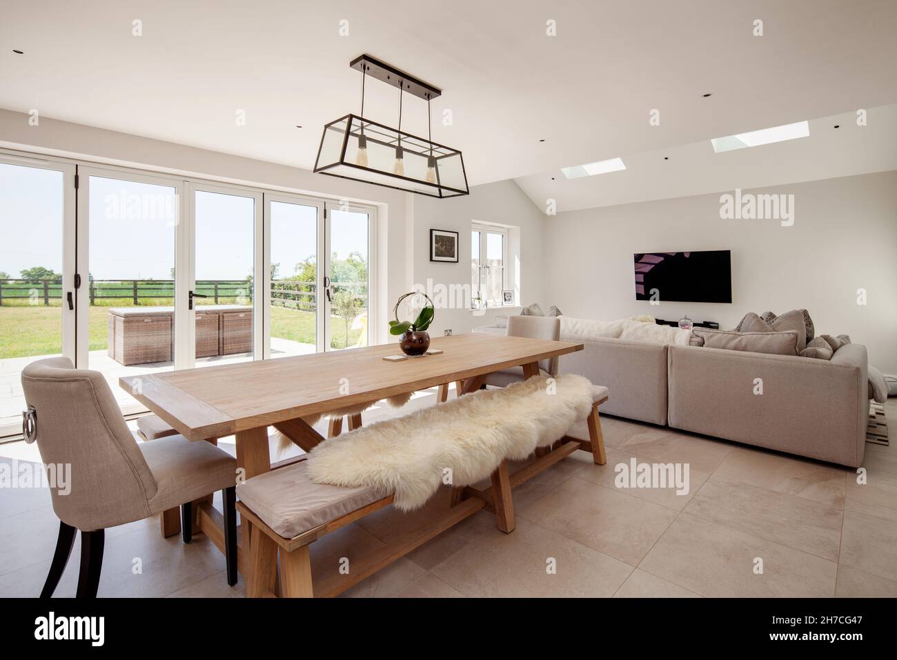 Lawshall, Suffolk, England - May 29 2020: Aspirational dining family room  with large dining table and seating area in front of tv with bifold doors  Stock Photo - Alamy
