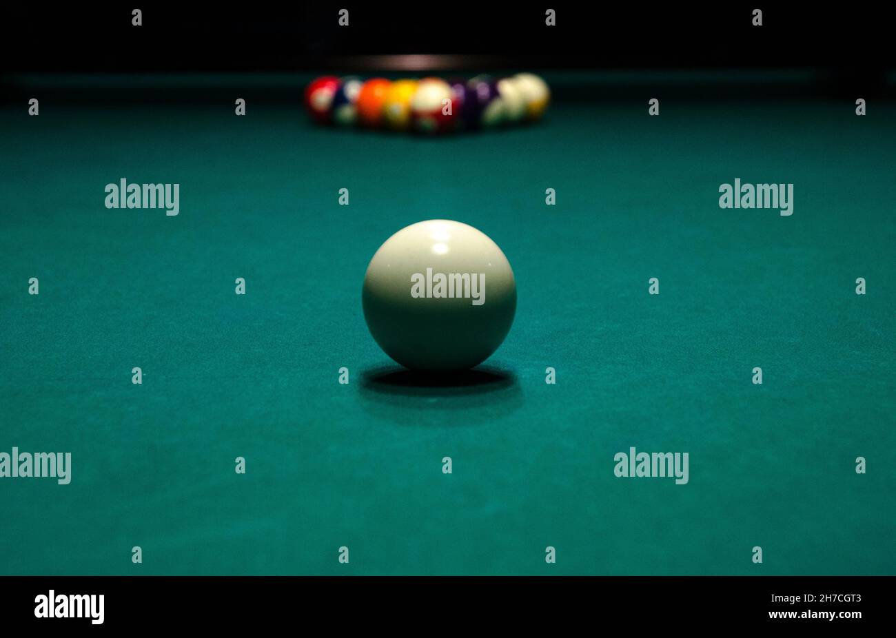Billiard balls on a green pool table with a white ball in front of the ...