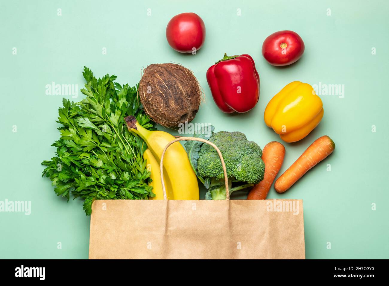 Eco friendly paper shop bag with raw organic green vegetables isolated on green background Flat lay, top view Zero waste, plastic free concept Stock Photo