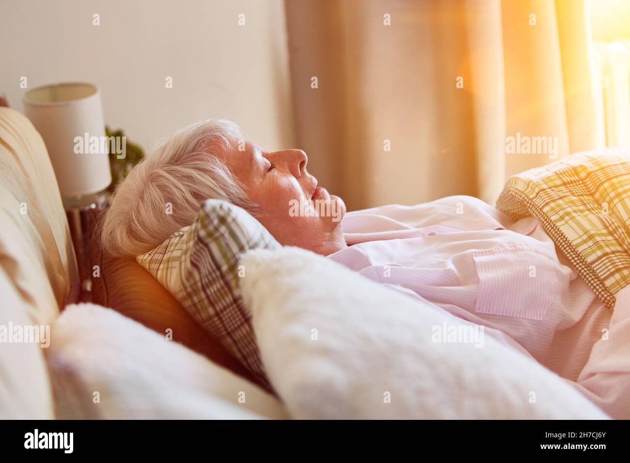 Old woman at noon while sleeping in bed in the old people's home Stock Photo