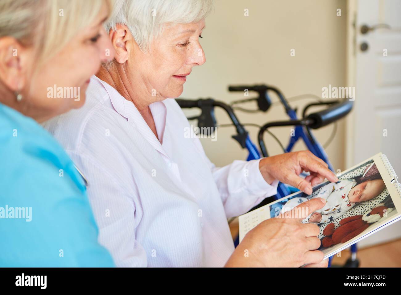 Demented elderly woman shows geriatric nurse photos of granddaughter as baby aif calendar Stock Photo