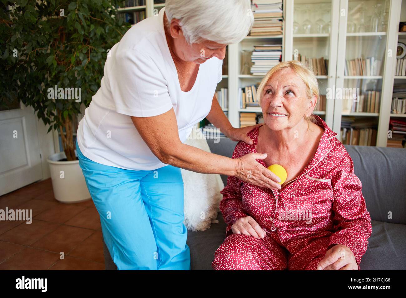 Elderly woman receives a trigger point massage as acupressure with a small massage ball Stock Photo