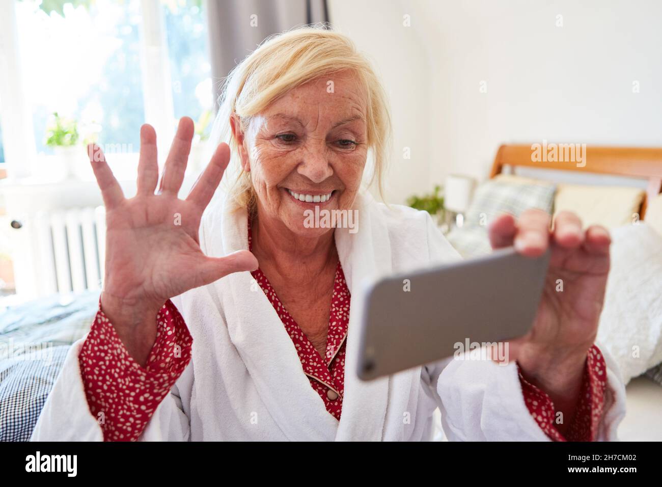 Happy senior woman in nursing home is video chat with family on smartphone Stock Photo