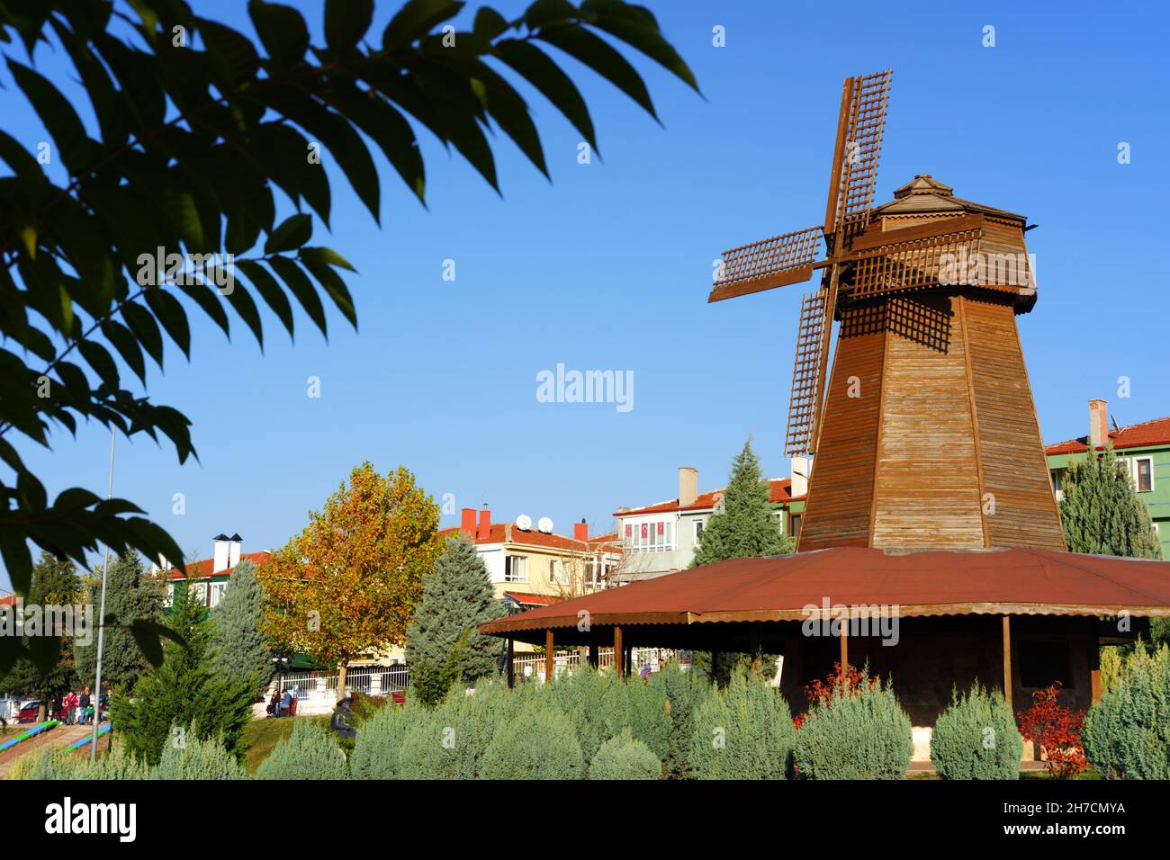 Retro wooden windmill behind green leaves in Eskisehir Selale Park Eskisehir Turkey Stock Photo