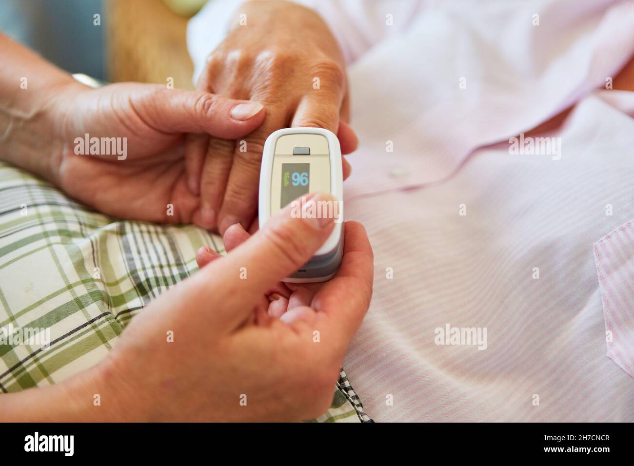 Oxygen saturation in a patient in the hospital is measured with a pulse oximeter Stock Photo
